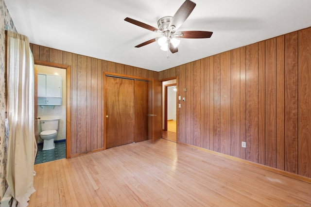 11 Jamestown Rd, Hamden, CT 06518 - unfurnished bedroom featuring hardwood / wood-style floors, wood walls, connected bathroom, a closet, and a ceiling fan