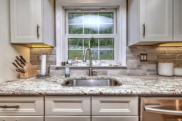 220 Northwood Dr, Guilford, CT 06437 - kitchen with a sink, stainless steel dishwasher, white cabinetry, light stone counters, and backsplash