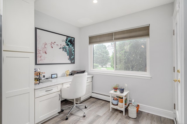 office area featuring light wood-style flooring, built in desk, a baseboard radiator, and baseboards