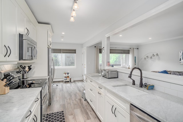 kitchen with stainless steel appliances, a sink, plenty of natural light, white cabinets, and recessed lighting