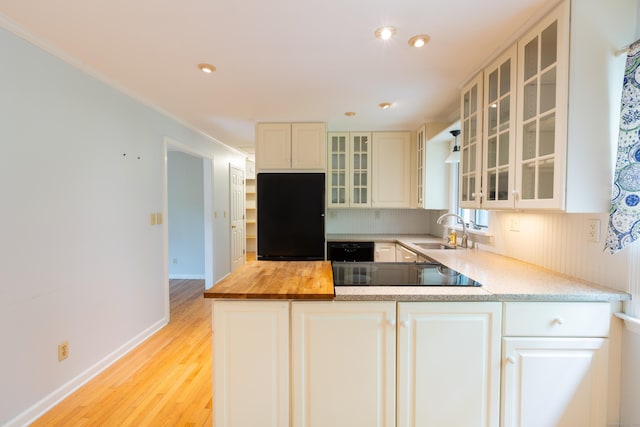 138 White Birch Dr, Guilford, CT 06437 - kitchen featuring black appliances, a sink, wooden counters, light wood finished floors, and glass insert cabinets