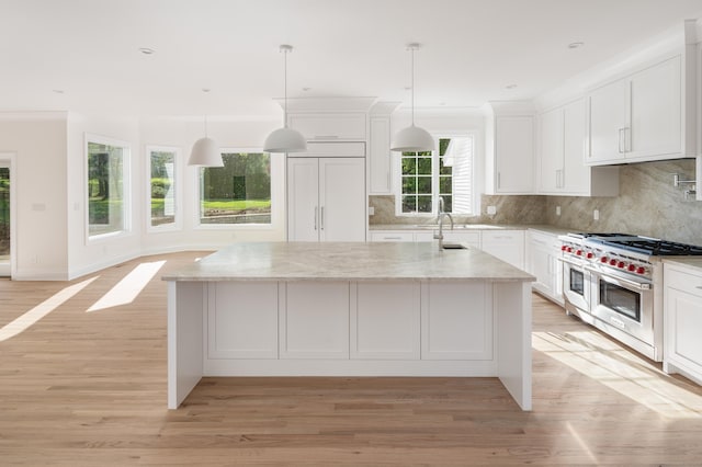 19 Stone Fence Ln, Stamford, CT 06903 - kitchen featuring range with two ovens, a sink, white cabinets, a kitchen island with sink, and light wood-style flooring