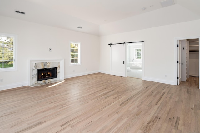 19 Stone Fence Ln, Stamford, CT 06903 - unfurnished living room featuring light wood-type flooring, a high end fireplace, a barn door, baseboards, and lofted ceiling
