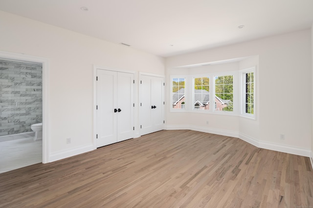 19 Stone Fence Ln, Stamford, CT 06903 - unfurnished bedroom featuring multiple closets, light wood finished floors, baseboards, and ensuite bath