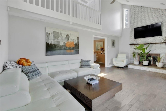 living area featuring a high ceiling, wood finished floors, a fireplace, and baseboards