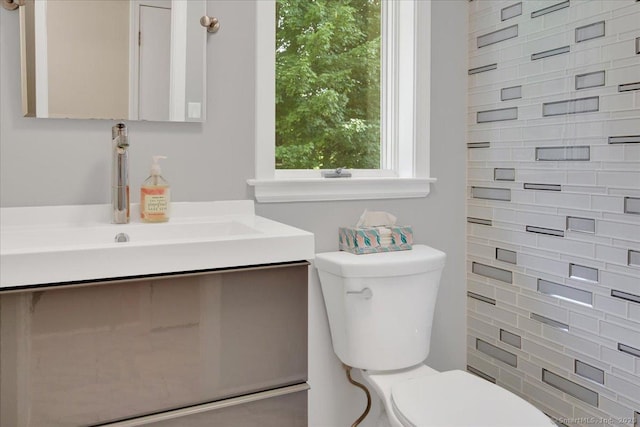half bathroom with toilet, backsplash, and vanity