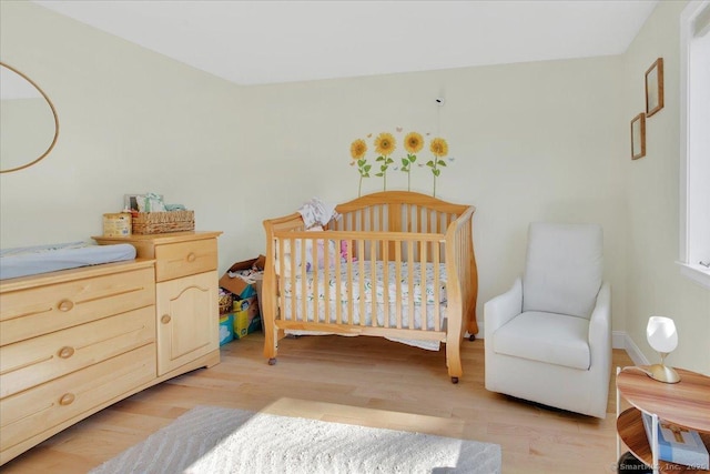 bedroom with light wood finished floors and a nursery area