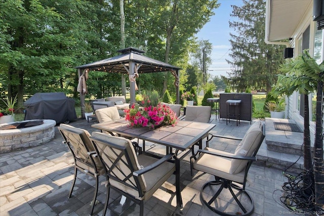 view of patio / terrace featuring outdoor dining area, a fire pit, area for grilling, and a gazebo