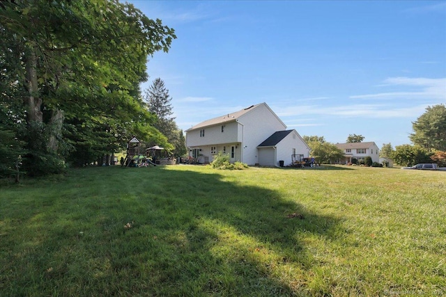 view of grassy yard featuring a playground and a garage