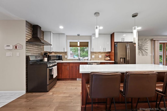 14 Stakey Farm Rd, Southington, CT 06489 - kitchen featuring stainless steel appliances, wall chimney range hood, light countertops, light wood finished floors, and a kitchen breakfast bar