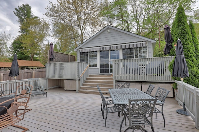 wooden deck featuring a sunroom, outdoor dining area, fence, and stairs