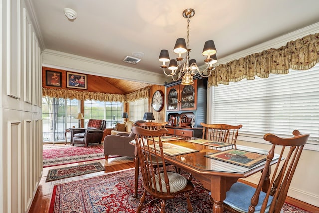 dining space featuring wood finished floors, a chandelier, and crown molding