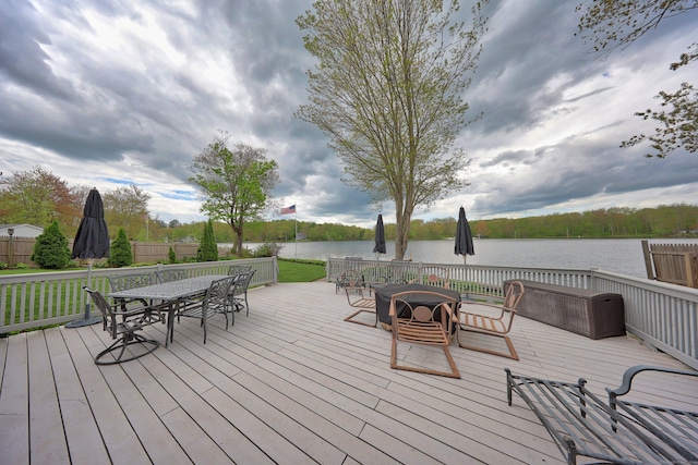 deck featuring outdoor dining space and a water view