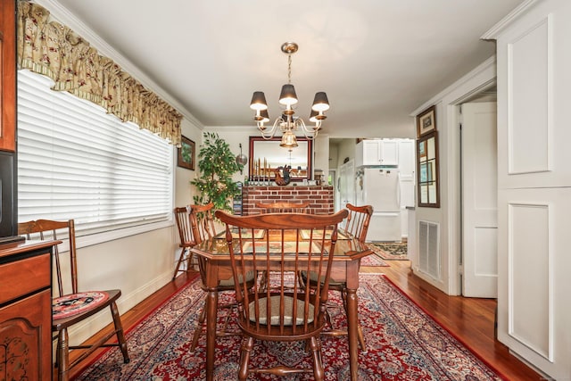 dining room with a chandelier, wood finished floors, baseboards, and ornamental molding