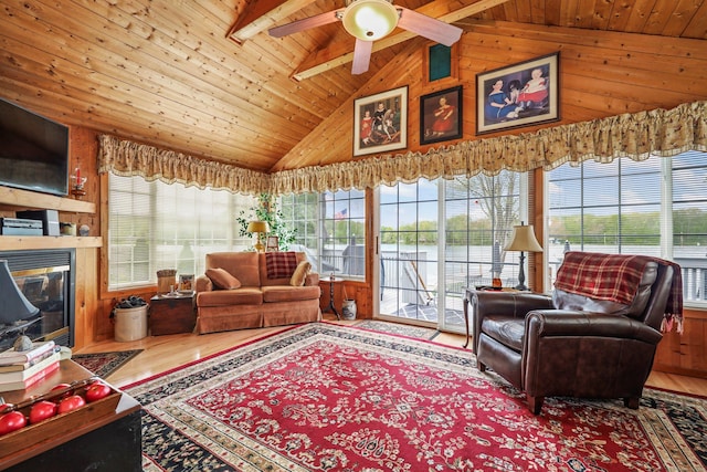 living area featuring plenty of natural light, wooden ceiling, wooden walls, a ceiling fan, and wood finished floors