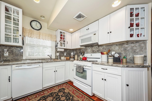 kitchen featuring white appliances, a sink, white cabinetry, glass insert cabinets, and recessed lighting