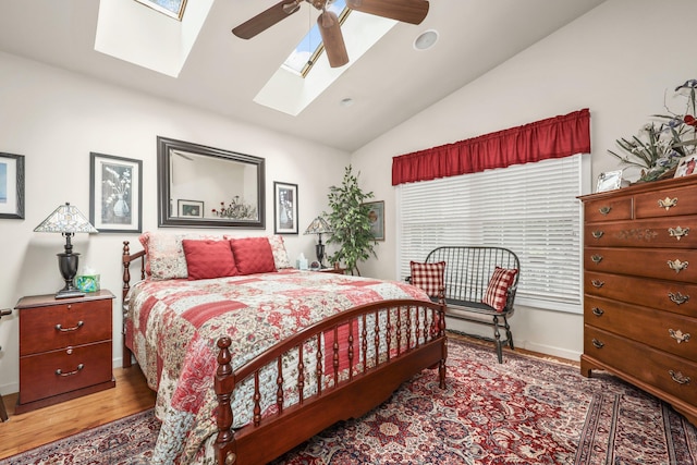 bedroom featuring a skylight, vaulted ceiling, wood finished floors, baseboards, and a ceiling fan