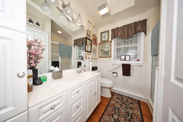 bathroom featuring a shower stall, toilet, vanity, wainscoting, and wood finished floors