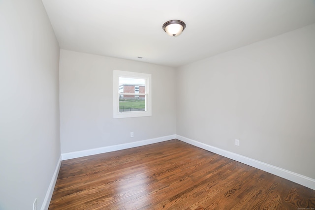 spare room with dark wood-style floors and baseboards