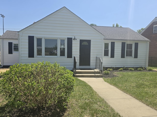 bungalow featuring a front yard and a shingled roof