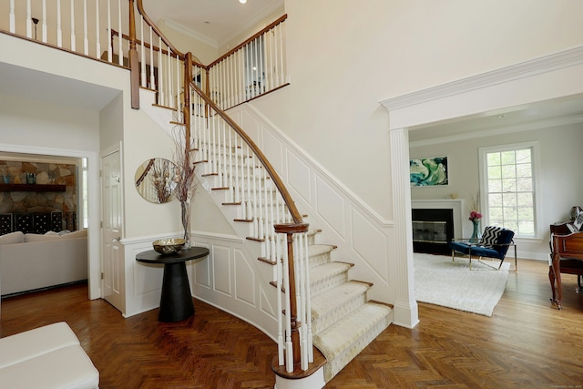110 Nursery Rd, Ridgefield, CT 06877 - staircase featuring a towering ceiling, a decorative wall, a glass covered fireplace, crown molding, and a wainscoted wall