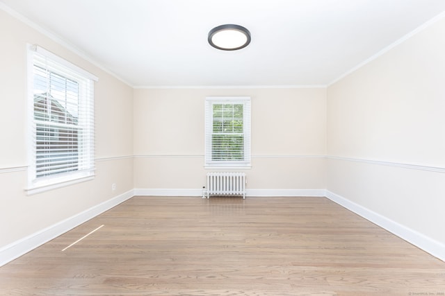 spare room with radiator heating unit, crown molding, baseboards, and light wood finished floors