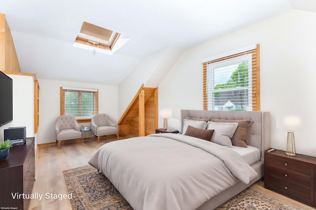 bedroom featuring a skylight, vaulted ceiling, multiple windows, and light wood-style floors