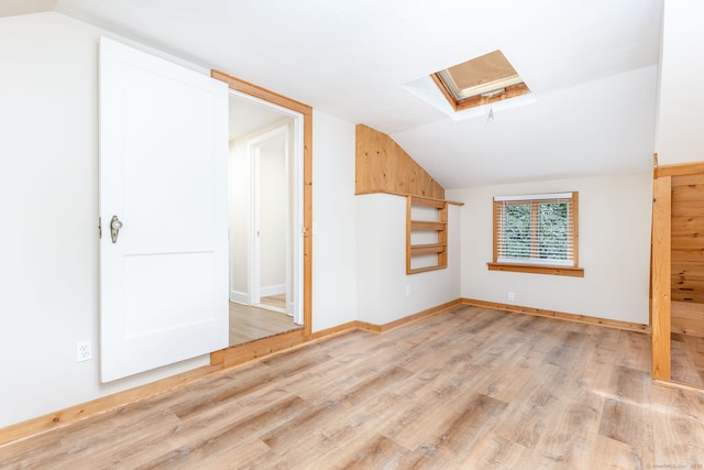 bonus room featuring a skylight, lofted ceiling, wood finished floors, and baseboards