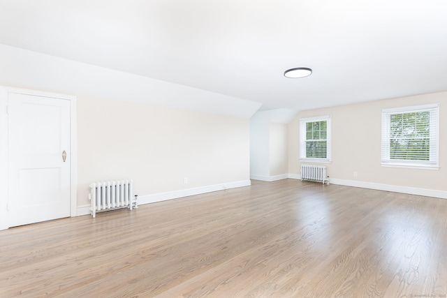 additional living space with radiator, wood finished floors, lofted ceiling, and baseboards