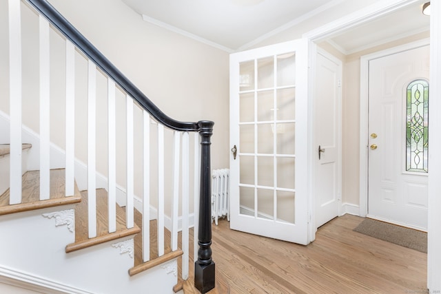 foyer featuring light wood-style flooring, ornamental molding, stairs, and radiator heating unit