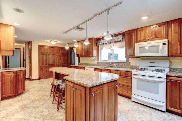 39 Eastgate Ln, Enfield, CT 06082 - kitchen with white appliances, a center island, brown cabinets, a sink, and light stone countertops