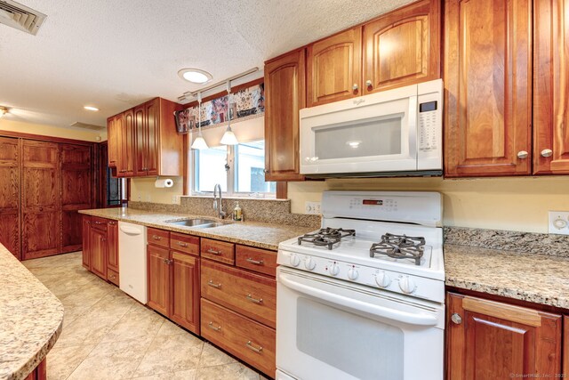 39 Eastgate Ln, Enfield, CT 06082 - kitchen with white appliances, a sink, brown cabinetry, a textured ceiling, and light stone counters