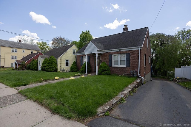 bungalow-style home with brick siding, a chimney, asphalt driveway, and roof with shingles