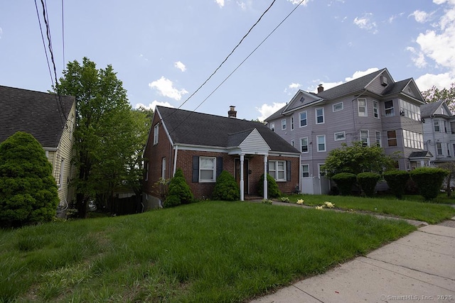view of front of property with brick siding, a chimney, and a front yard