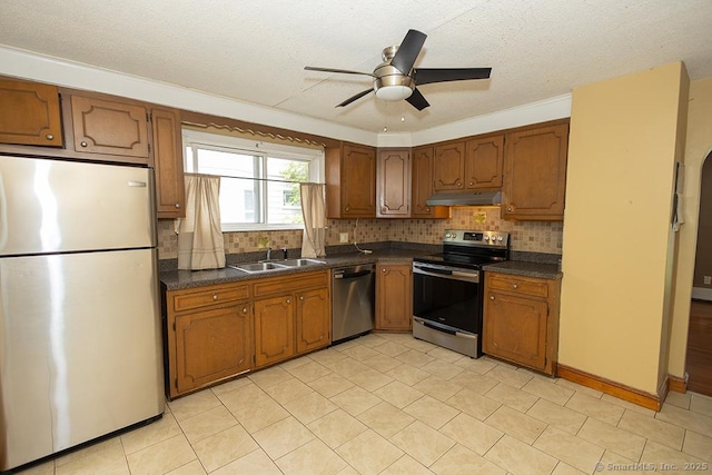 kitchen with stainless steel appliances, under cabinet range hood, a sink, dark countertops, and ceiling fan