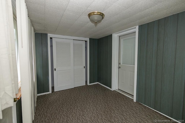 unfurnished bedroom featuring a closet, carpet, and wooden walls