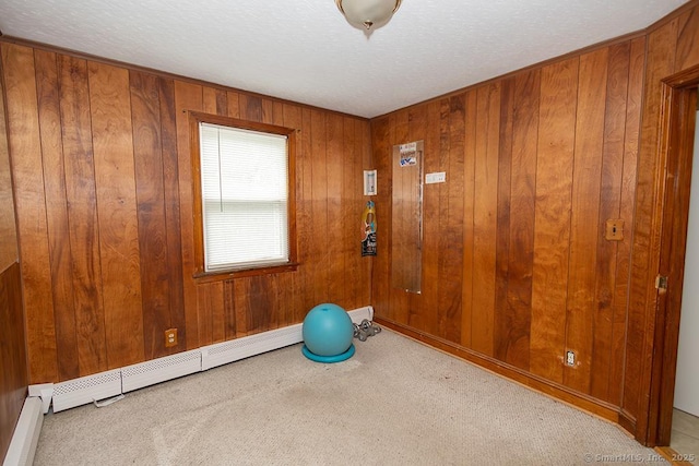 exercise area with carpet, baseboard heating, a textured ceiling, wood walls, and a baseboard radiator