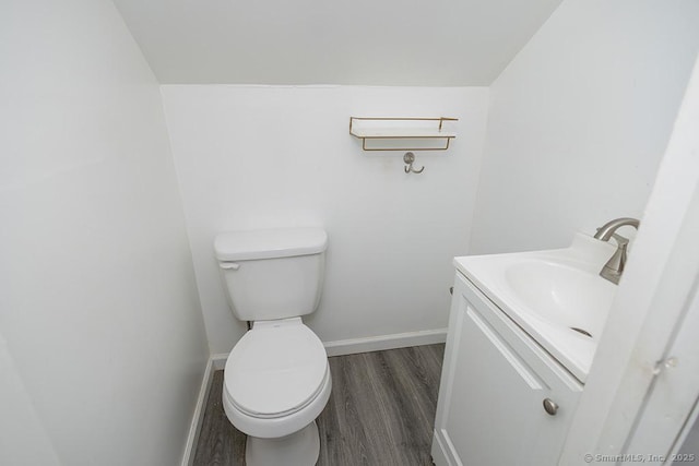 bathroom with wood finished floors, vanity, baseboards, and toilet