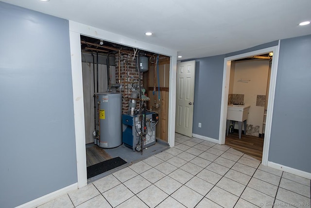 finished below grade area featuring gas water heater, a heating unit, baseboards, recessed lighting, and light tile patterned floors