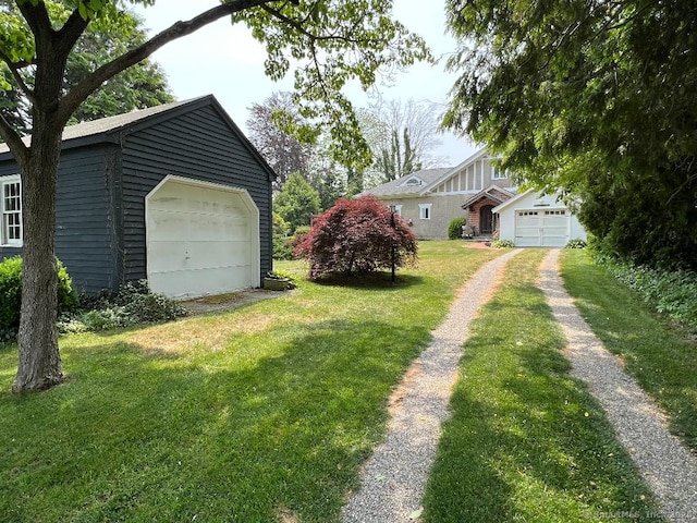 view of green lawn with a garage and driveway