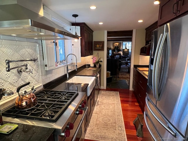 kitchen with appliances with stainless steel finishes, extractor fan, dark countertops, decorative backsplash, and dark wood-type flooring