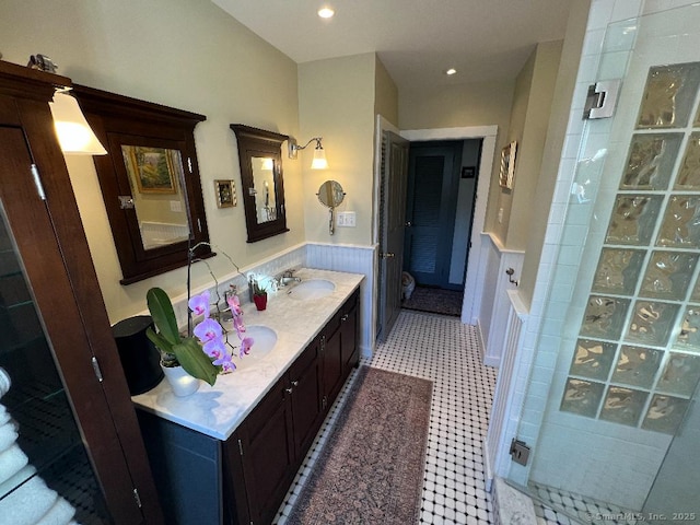 bathroom featuring a tile shower, wainscoting, vanity, and recessed lighting