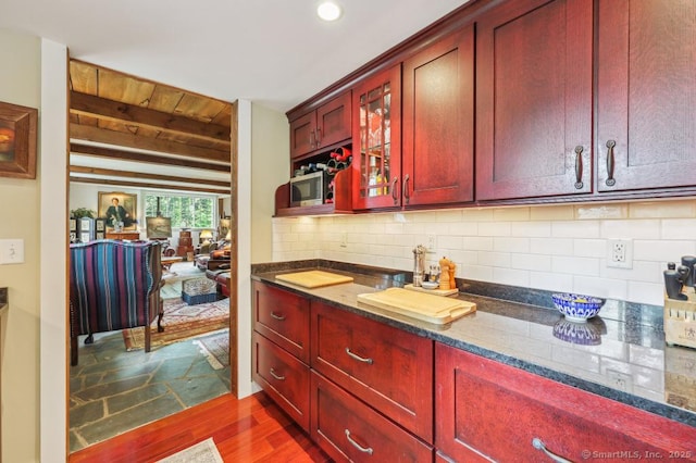9 Columbus Ave, East Lyme, CT 06357 - kitchen with reddish brown cabinets, dark wood-style flooring, dark stone counters, tasteful backsplash, and beam ceiling