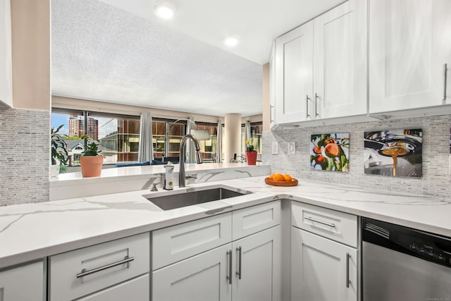 127 Greyrock Pl Unit 502, Stamford, CT 06901 - kitchen featuring a sink, stainless steel dishwasher, backsplash, white cabinets, and a textured ceiling