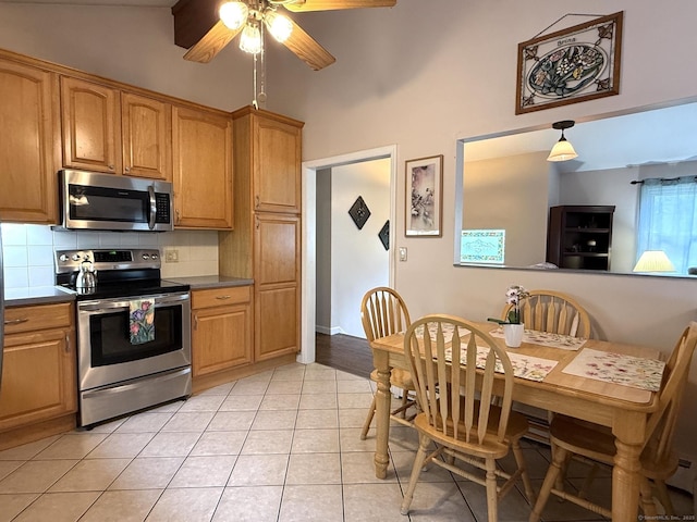 kitchen featuring appliances with stainless steel finishes, high vaulted ceiling, light tile patterned flooring, a ceiling fan, and backsplash