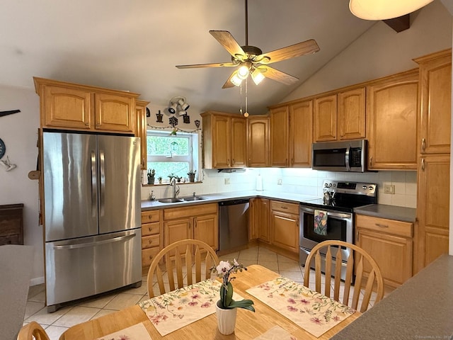 kitchen featuring appliances with stainless steel finishes, a sink, light tile patterned floors, decorative backsplash, and lofted ceiling