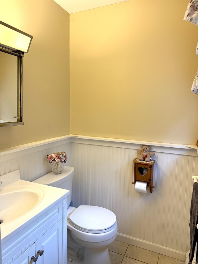 bathroom with wainscoting, toilet, tile patterned flooring, and vanity
