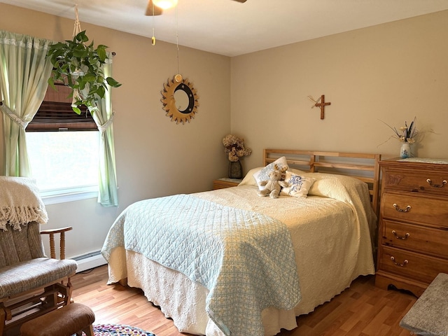 bedroom with wood finished floors and baseboard heating