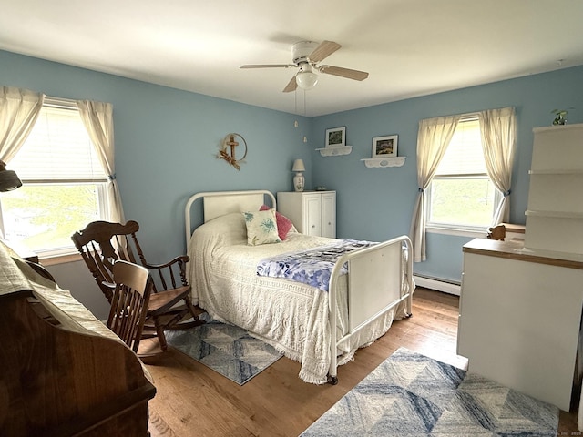 bedroom with a baseboard heating unit, wood finished floors, and a ceiling fan