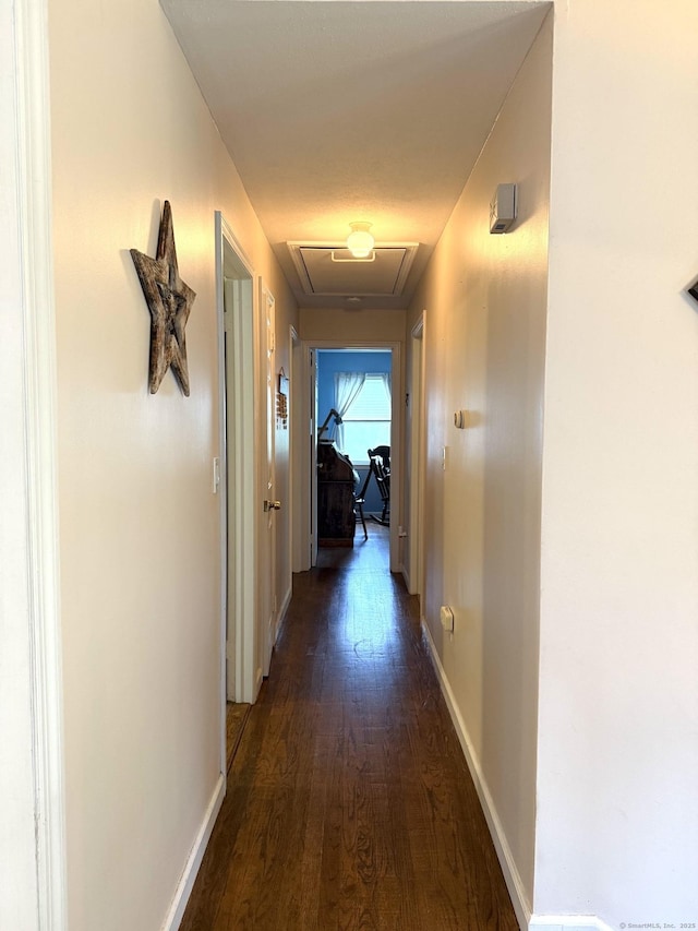 hallway with dark wood-style flooring and baseboards